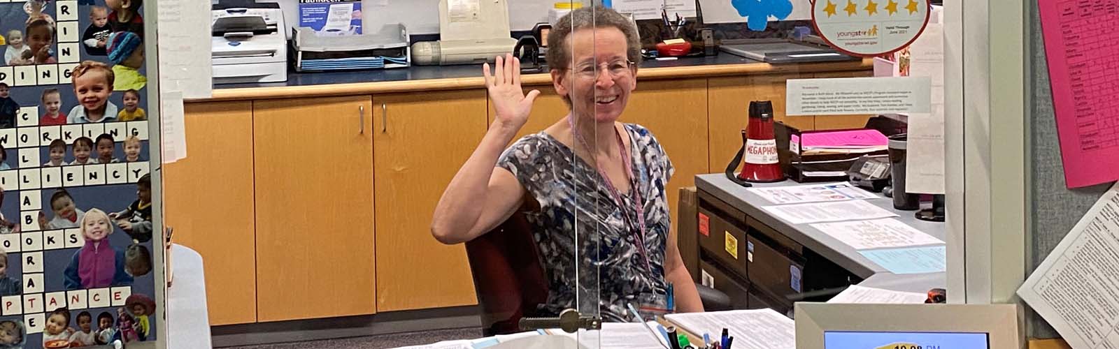 Staff waving at front desk to greet families coming to the Waisman Early ChildhoodnCenter.